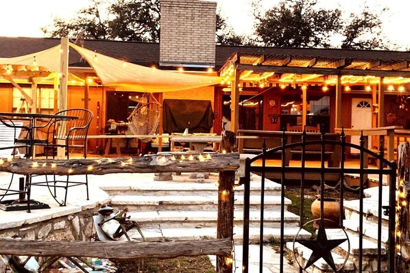 An outdoor seating area with tables and chairs, a covered patio, and a decorative fence with lights.