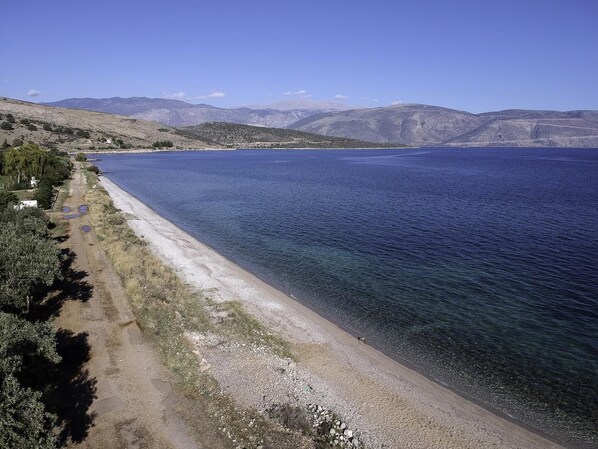A coastal road with a beach, clear blue water, and distant mountains. - Galaxidi Mansion, Private villa (Galaxidi)