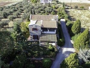 A two-story stone house with a tiled roof, surrounded by lush greenery and olive trees. - Galaxidi Mansion, Private villa (Galaxidi)