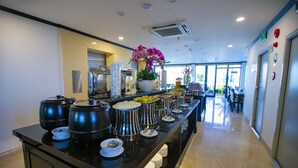 A buffet area with various food items and a potted orchid. - Pharaoh Boutique Hotel Danang (Da Nang)