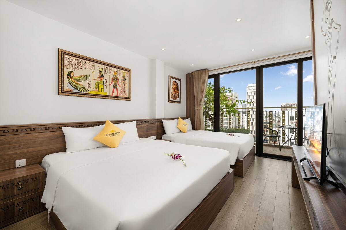 Een hotelkamer met twee bedden, een groot raam met uitzicht op de stad en kunstwerken aan de muur.