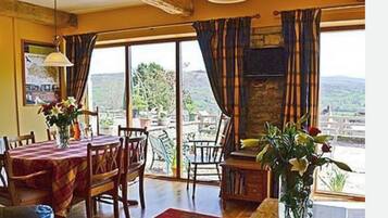 A dining area with a table set for two, a fireplace, and a view of the outdoors.