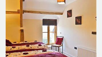 A bedroom with a bed, a chair, a window, and artwork on the wall.