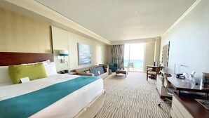 A hotel room with a large bed, a desk, a chair, and a view of the ocean. - Ocean View Suite at T. International STR-02496 (Sunny Isles)