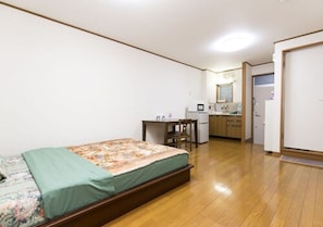 Ein Schlafzimmer mit Bett, Schreibtisch und einer Küchenzeile.