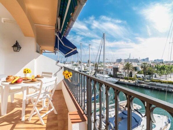 Un balcon avec une table dressée pour le petit-déjeuner, donnant sur une marina avec des bateaux et une vue sur la ville.