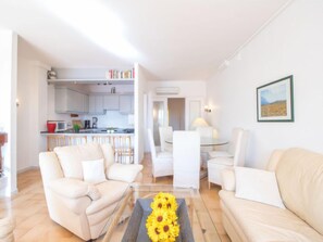 Un salon moderne avec une table basse en verre, deux canapés et un coin repas comprenant une table et des chaises.