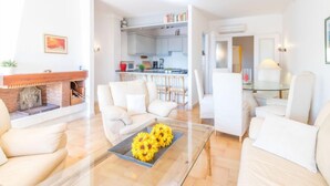 A modern living room with a glass coffee table, white sofas, and a fireplace. - Caballito de Mar by Interhome (Empuriabrava)