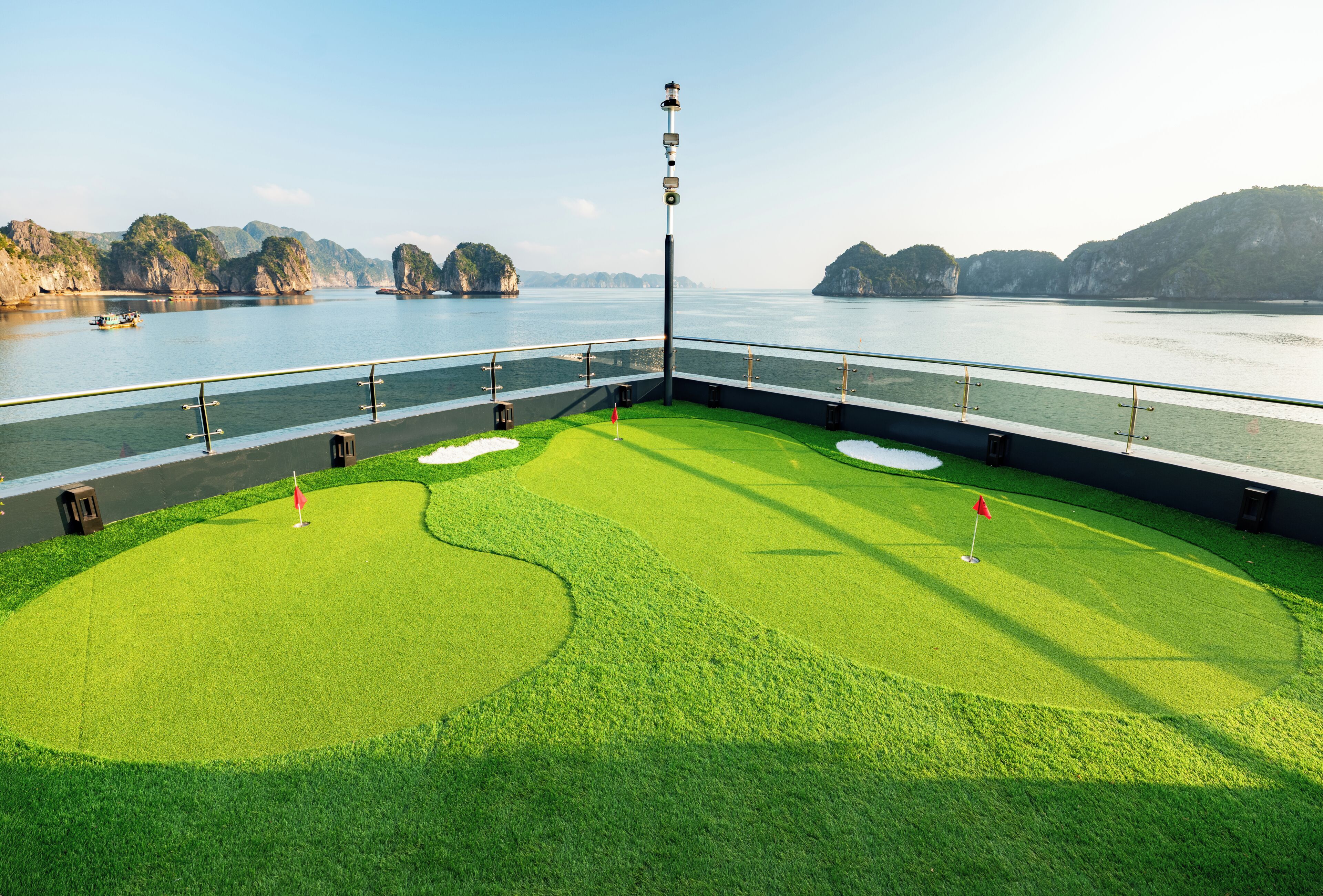 Campo de golf con un cuerpo de agua y paisaje rocoso al fondo.