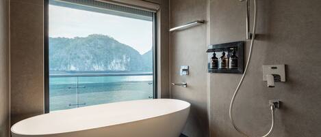 Une salle de bain moderne dotée d’une baignoire sur pieds, d’une douche et offrant une vue sur une côte montagneuse.