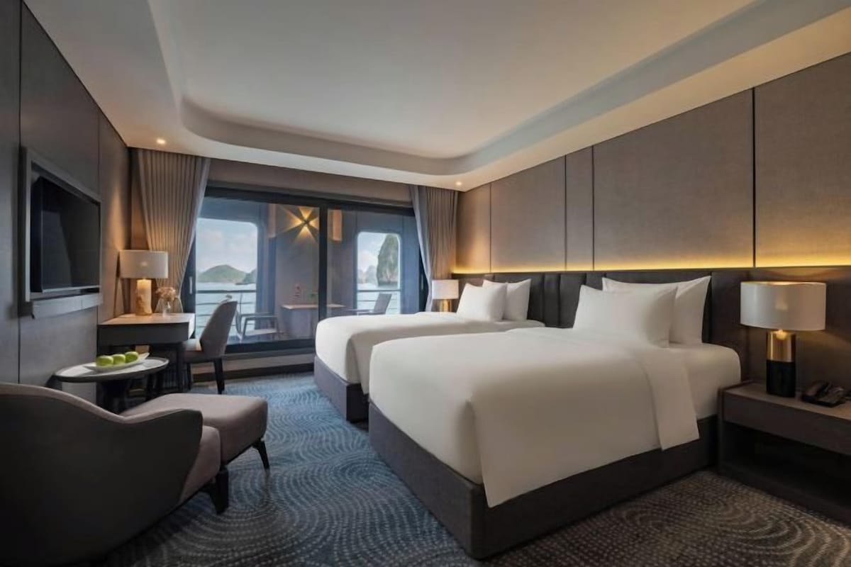 A hotel room with a large bed, a desk, a chair, and a view of the outdoors.