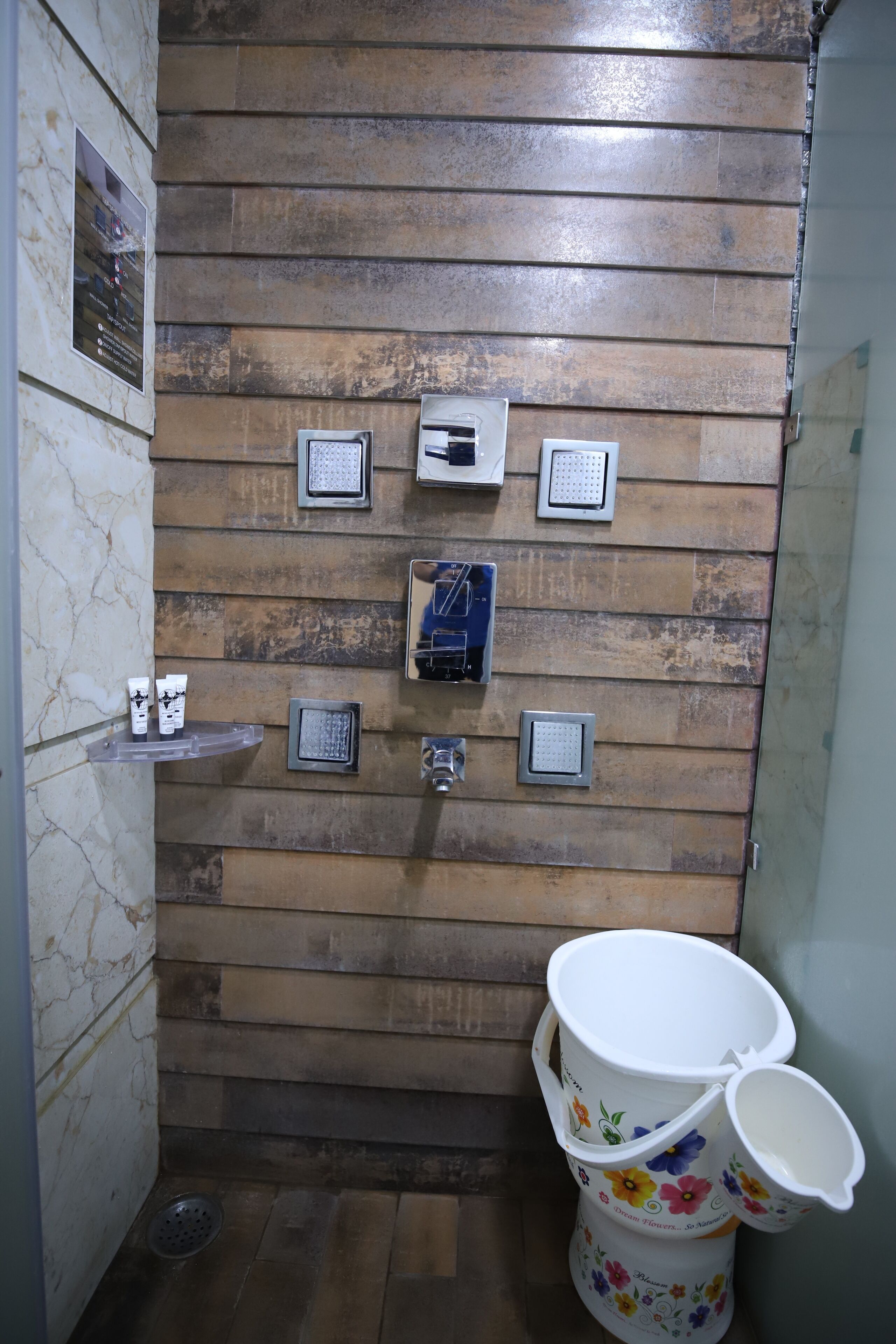 Un baño con pared de madera, un inodoro con diseño floral y un estante con artículos de aseo.