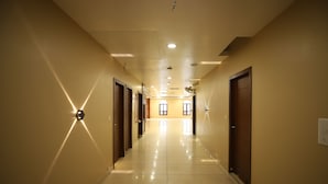 A hotel hallway with a tiled floor, wooden doors, and recessed lighting. - Hotel Visit (Barnala)