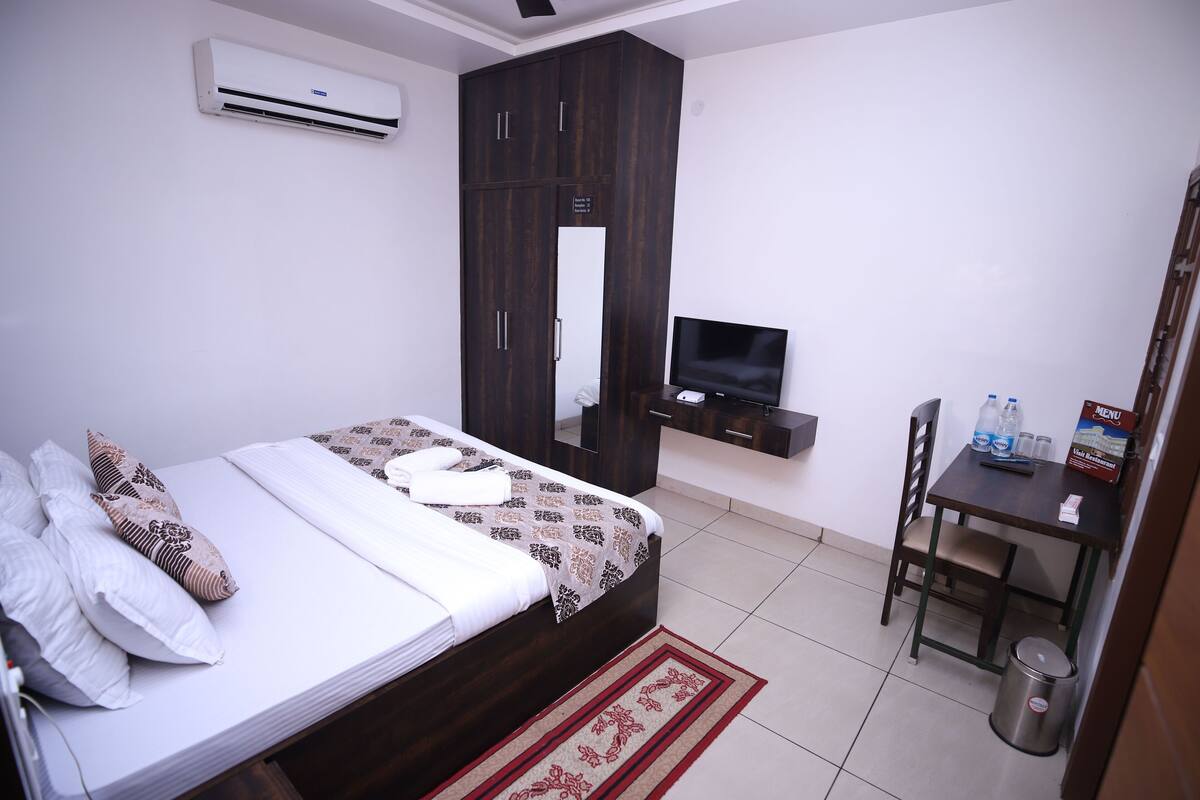 Une chambre à coucher avec un lit, une télévision, un bureau et une armoire.