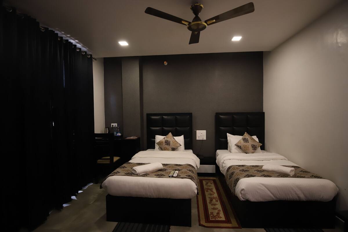 Une chambre d’hôtel avec deux lits, un ventilateur de plafond et une table de chevet avec une lampe.
