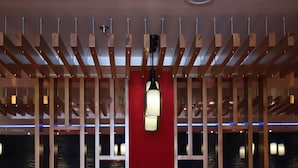 A restaurant with a long wooden table, red upholstered chairs, and a red wall with a view of water. - Hotel Visit (Barnala)