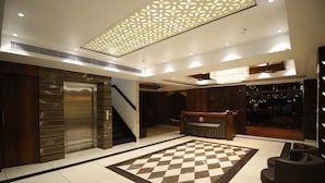 A lobby with a checkered floor, a reception desk, a staircase, and an elevator. - Hotel Visit (Barnala)