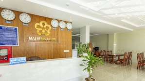 A hotel reception area with a wooden reception desk, multiple clocks displaying different time zones, a reception sign, and a dining area with wooden tables and chairs. - Mai Hùng Hotel (Phu Quoc)