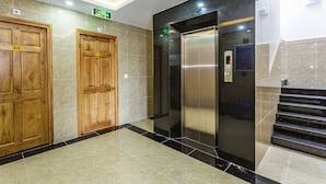 A modern elevator with a digital display, wooden doors with numbers, and a marble floor. - Mai Hùng Hotel (Phu Quoc)