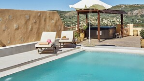 A pool area with lounge chairs and a hot tub, surrounded by a pergola and a mountainous backdrop. - Four bedroom Mouri villas complex of 18th century (CPM2+9RH Mouri, Greece)