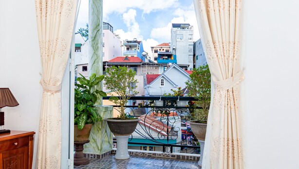Un balcone con piante in vaso, vista su edifici e ringhiera.