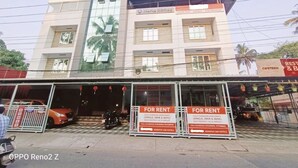 A building with multiple floors, featuring a large glass facade and several balconies. There are signs advertising fully furnished apartments for rent.