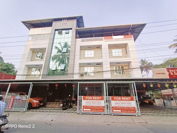 A building with multiple floors, featuring a large glass facade and several balconies. There are signs advertising fully furnished apartments for rent.