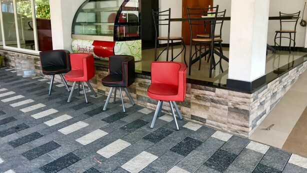 A seating area with chairs and a table, a glass partition, and a vehicle parked outside.