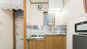 A compact kitchen with wooden cabinets, a microwave, and a small sink. - Centrally Located Deluxe Furnished.3 (Tokyo)
