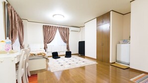 A room with a bed, a desk with chairs, a TV, a wardrobe, and a washing machine. - Centrally Located Deluxe Furnished.3 (Tokyo)