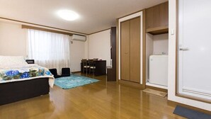 A bedroom with a bed, a desk, a chair, a wardrobe, and a refrigerator. - Centrally Located Deluxe Furnished.4 (Tokyo)