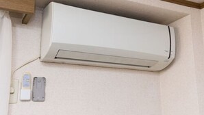 A white wall-mounted air conditioner with a control panel and a power outlet below it. - Centrally Located Deluxe Furnished.4 (Tokyo)
