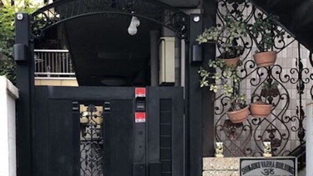 A black gate with a decorative metal design, leading to a stone staircase with a sign above it. - Centrally Located Deluxe Furnished.4 (Tokyo)