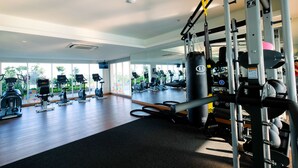 A gym with various exercise machines, a mirrored wall, and large windows. - Wonderful 2BR at Menteng Park Apartment (Jakarta)