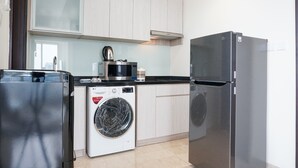 Een kleine keuken met een wasmachine, een koelkast en een magnetron.