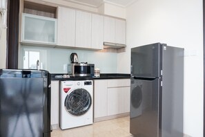 Une cuisine compacte équipée d’un lave-linge, d’un réfrigérateur et d’un four à micro-ondes.
