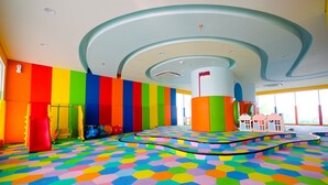 Ein farbenfroher Spielbereich mit sechseckigem Fußbodenmuster, einer zentralen Säule und einer gewölbten Decke.