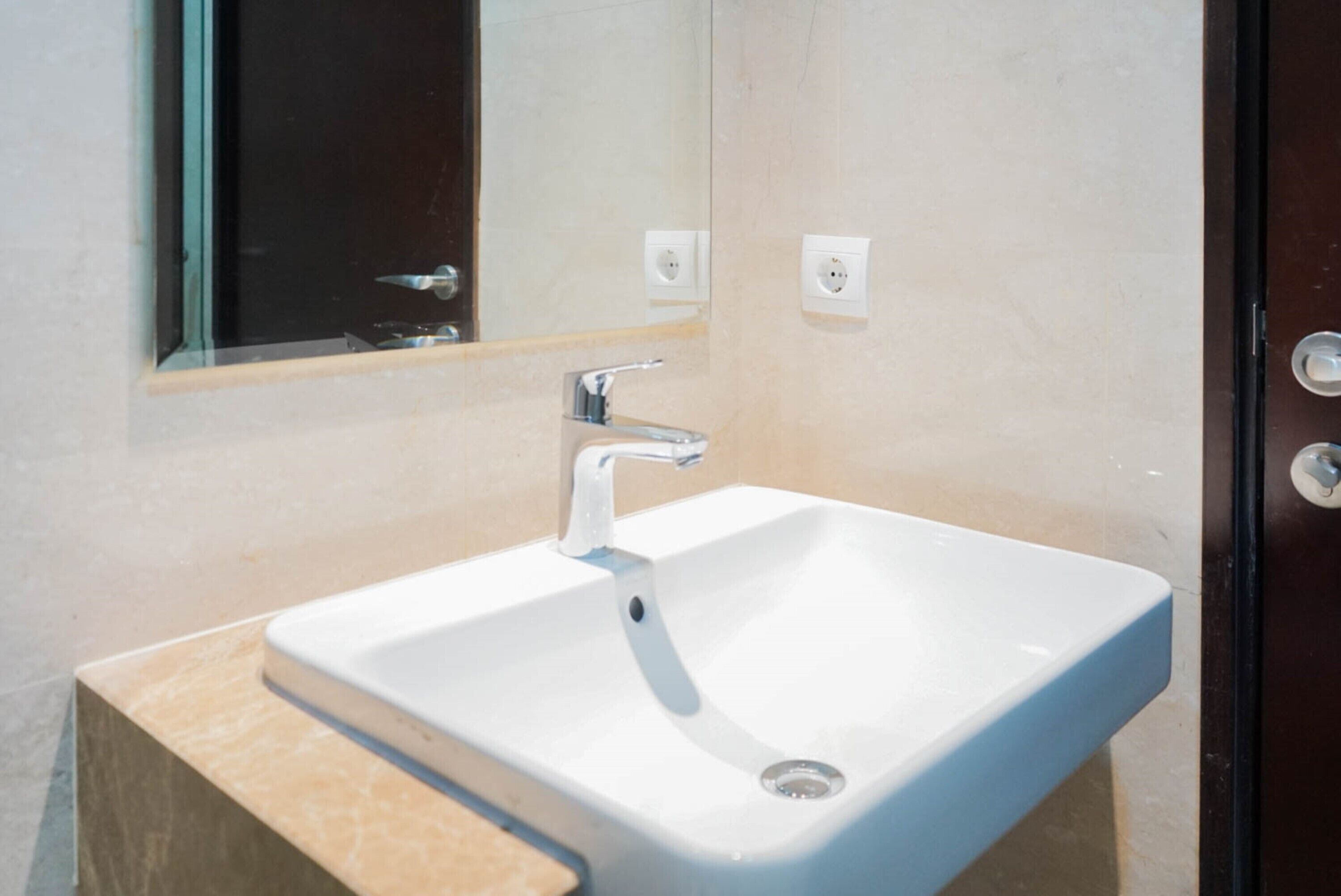Ein Badezimmer mit Waschbecken, Spiegel und Steckdose.
