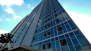 Ein hohes, modernes Gebäude mit Glasfassade und blauem Himmel im Hintergrund.