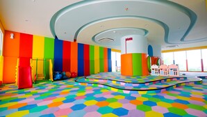 A colorful play area with hexagonal flooring, a central pillar, and a curved ceiling design. - Newly Furnished Studio Apartment at Menteng Park (Jakarta)