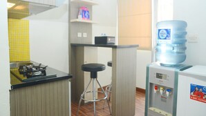 A kitchenette with a gas stove, a water dispenser, and a stool. - Best Choice 2BR Apartment at Menteng Square (Jakarta)