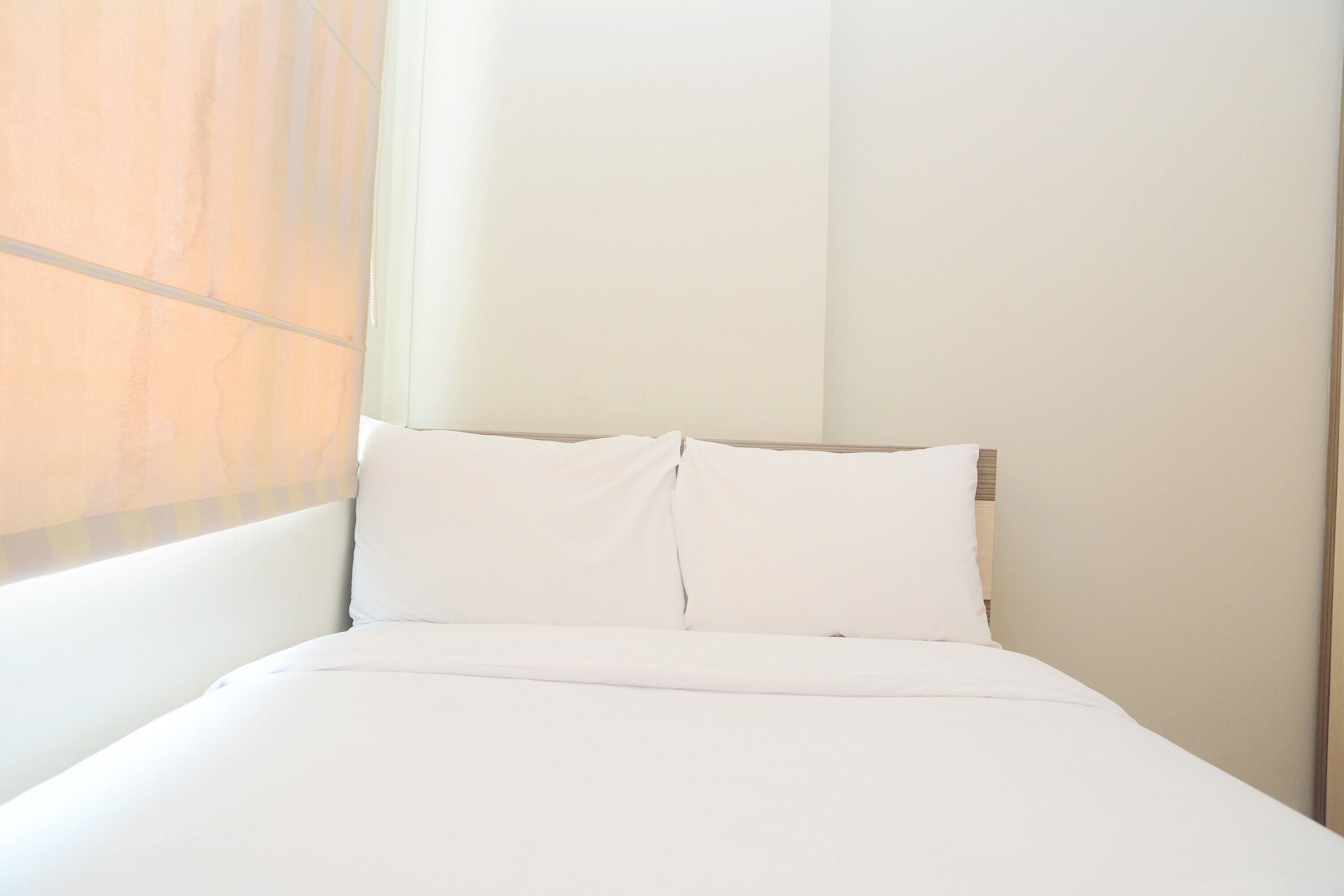 A neatly made bed with white linens in a hotel room.
