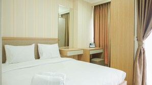 Ett hotellrum med en säng, ett skrivbord, en spegel och ett fönster med gardiner.
