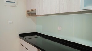Una cucina con pensili in legno chiaro, un piano di lavoro nero e un termostato fissato al muro.