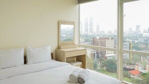 A hotel room with a large window, a bed with white linens, a wooden desk, and a mirror. - Wonderful 2BR Menteng Park Apartment with Private Lift (Jakarta)