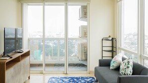 A modern living room with a grey sofa, a flat-screen TV, and a wooden cabinet. - Wonderful 2BR Menteng Park Apartment with Private Lift (Jakarta)