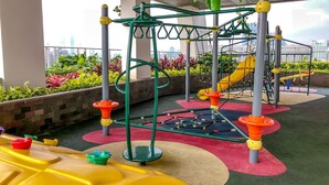 Un espace de jeux extérieur comprenant une structure d’escalade, des toboggans et un revêtement de sol coloré.
