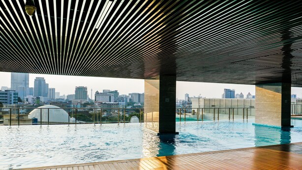 Une piscine intérieure avec vue sur la ville, dotée d’une terrasse en bois et d’un design moderne au niveau du plafond.