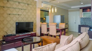 A modern living room with a TV, sofa, and a dining area with chairs and a table.
