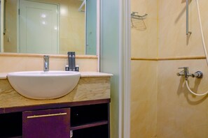 Un baño con lavamanos blanco, espejo y zona de ducha.